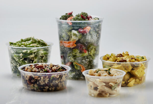 Deli containers holding pasta, broccoli, rice, and green beans.