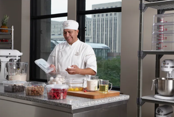 Chef standing over filled round clear food storage containers